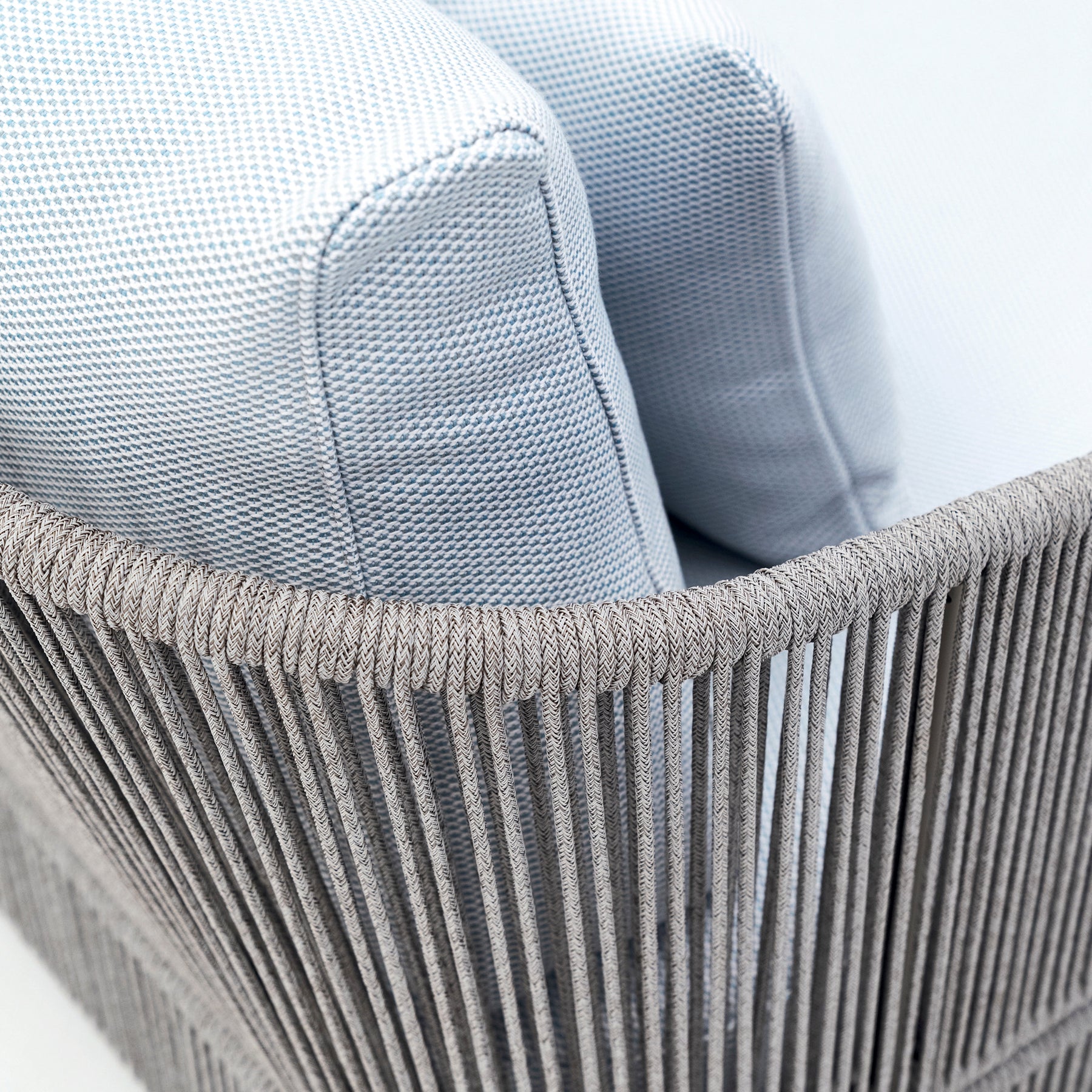 Close-up of a textured gray chair with a woven base.