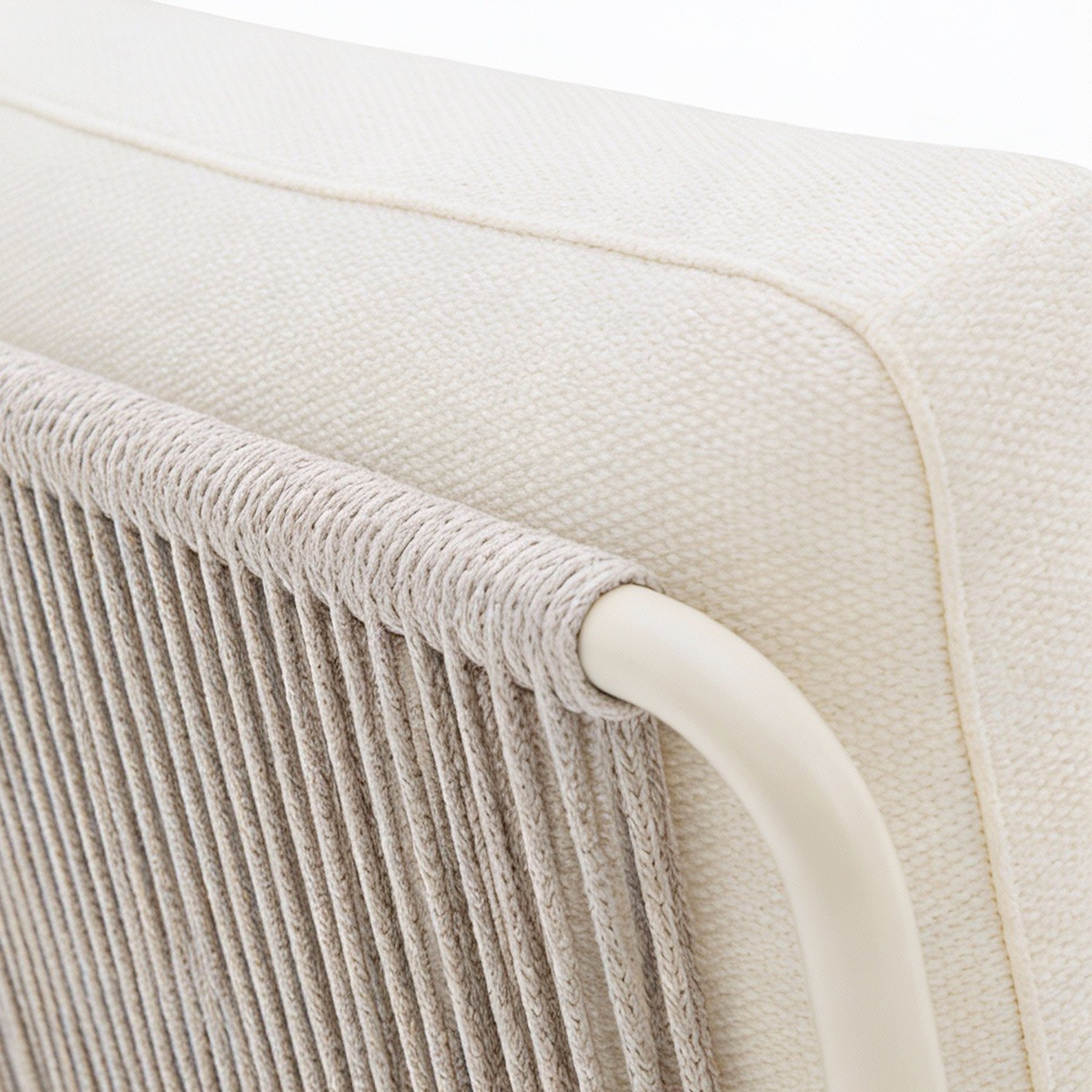 Close-up of a beige chair with woven armrest and white frame.