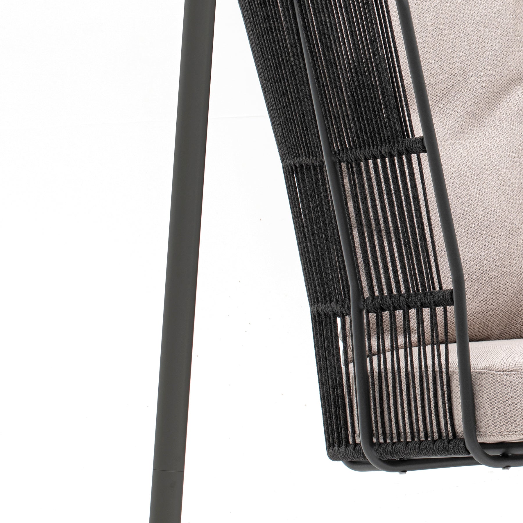 Close-up of a black wicker chair with a beige cushion on a white background