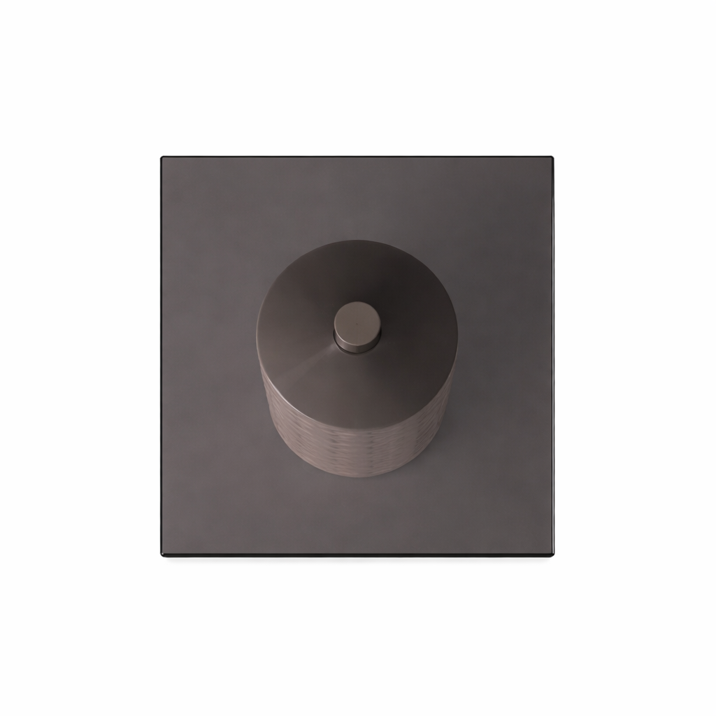 Dark gray cylindrical object on a matching square base against a white background
